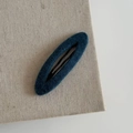 Detail of dark blue plush fabric BB hair clip with textured felt finish on beige fabric - Oval Hair Clip / Blue