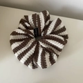 Detailansicht eines gestrickten gestreiften Haargummis mit einem kleinen Stoffetikett - Weiß Kaffee Gestreift
