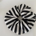 Nahaufnahme eines gestreiften Strick-Scrunchies mit Stoffstruktur und Materialetikett - Weiß-schwarze Streifen