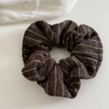 Macro detail of dark brown and yellow striped knitted hair scrunchie fabric texture - Coffee