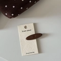 Detailed macro view of a glossy dark brown oval hair clip on a minimalist display card - Solid Coffee Oval Hair Clip