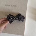 Detailed view of polka dot bow hair clip with silver buckle on elegant fabric - Black White Polka Dot