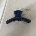 Detail of blue denim fabric hair claw clip with yellow contrast stitching on a book - Denim Acrylic Hanger Shape Claw Clip