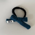Detalle de coletero negro plisado con lazo azul y etiqueta tejida con texto Nice - 3# Lazo Azul Goma Pelo