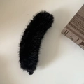 Dettaglio del fermaglio a banana in pelliccia nera su uno sfondo di libro vintage - Nero