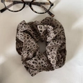 Haargummi mit Leopardenmuster und Brille auf strukturiertem Stoffhintergrund - Helles Leopardenmuster (Schlanker Stil)