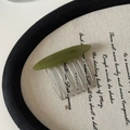 Dettaglio di un pettine verde oliva fatto a mano con sette denti in metallo argentato - Pettine per Capelli Curvo Verde