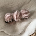 Detalle de la pinza para el pelo tipo banana en suave felpa rosa palo sobre fondo de tela - Pinza Banana Peluche Pompones Rayada Rosa