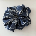 Detail view of denim blue scrunchie with white chain patterns and soft fabric pleats - Light Blue White Texture