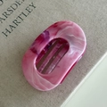 Detailed top view of a pink and white marble texture oval hair claw on a textured book - 7# Rose Red Oval Claw