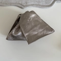 Detailansicht aus grauem Satinstoff mit geprägter 3D-Rosentextur und glänzender Oberfläche - Kaffeeblaue Blume