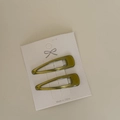 Close-up of olive green metal BB hair clips on a white texture presentation card - Mustard Green