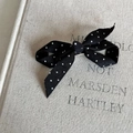 Vintage zwarte polkadot haarclip met zilveren BB-clip op linnen textuur achtergrond - Zwarte haarspeld met witte stippen strik
