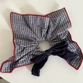 Dettaglio di scrunchie a quadretti bianco e nero con cuciture rosse e fiocco blu scuro - Scrunchie a Righe Nere