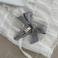 Detail of elegant grey satin bow hair clip on a minimalist white textured fabric - Gray