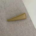 Detail einer matt-senfgrünen Dreiecks-Haarspange mit Ziernaht auf grauem Stoffhintergrund - Senfgelb