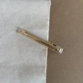 Detail shot of golden metal alligator hair clip with Handmade engraving on a textured surface - Bright Gold