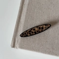 Detail van ovale haarklem met luipaardprint op beige stof met zwarte retro randen - Luipaard Lange Ovale Haarklem