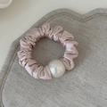 Detail shot of a soft champagne pink satin scrunchie with elegant large white pearl - Pink Pleated Artificial Pearl Scrunchie