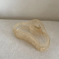 Detalle de la pinza para el pelo en resina champán con diseño curvo y elegante - Amarillo leche