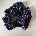 Detailed view of navy blue polka dot hair scrunchie with red zigzag stitched edge - Polka Dot Denim Scrunchie