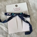 Navy blue floral fabric bow hair clip with colorful rhinestones on a white card display - Denim Bow Crystal