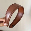 Detailed close-up of brown leather headband featuring fine stitching and smooth texture - Caramel color