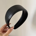 Close-up of a wide padded black leather headband with detailed visible stitching - Black