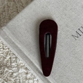 Gros plan d'une barrette goutte en velours bordeaux sur une boîte minimaliste - Pince à cheveux goutte d'eau rouge vin