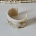 Dettaglio macro del bracciale largo in resina con texture marmoree crema e verdi e finitura - Bianco Crema (2# Grande)