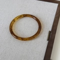 Primo piano del bracciale in resina ambra con trama marmorea su sfondo di tessuto grigio - Tartarugato (6# Piccolo)