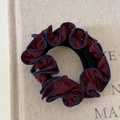 Retro bordeaux scrunchie met donkerblauwe ruches op een beige linnen doek - Steenrood Gegolfd Haarelastiekje