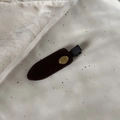 Détail de la pince à cheveux en velours marron foncé avec boucle dorée Smile Happy - Pince Floquée Brune Étiquette Or Sans Trace