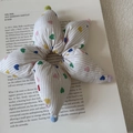 Close-up of heart-patterned striped scrunchie with colorful pom-poms on a book - White Stripe Heart Star Scrunchie