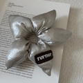 Close-up of a silver metallic padded star scrunchie on a book with Turner label - Solid Silver Star Scrunchie