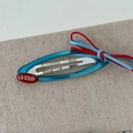 Detail of Korean-style blue BB hair clip with red and blue woven bow on grey fabric - Blue Clip Red Label