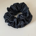 Gros plan d'un chouchou en tissu à carreaux bleu et noir avec étiquette de logo tissée - Style Plaid Bleu Marine
