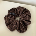 Close-up of brown leopard print velvet scrunchie with a black woven logo tag - 1# Flocked Leopard Print Scrunchie