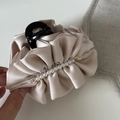 Detailopname van champagne satijnen haarklem met parels en een gouden metalen hanger - Broken Wit