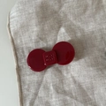 Detail shot of a dark red bow-shaped acetate hair clip with engraved lettering on linen - Wine Red Bow Hair Clip