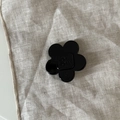 Detail of a shiny black acetate flower hair clip with wer wer text on linen background - Black Flower Clip