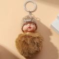 Cute sleeping baby plush keychain with brown knit hat, gold crown and fluffy fur pom-pom - Dark Brown