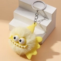 Detailed close-up of fluffy yellow monster keychain with large eyes and silver metal ring - Yellow