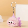 Close-up of pink plush monster keychain with big eyes, purple fins and silver chain - Pink