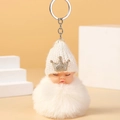 Detail eines schlafenden Baby-Plüsch-Schlüsselanhängers mit weißer Mütze und flauschigem Pompon - Weiß