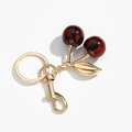 Detail view of red cherry keychain with marble effect resin fruit and gold metal leaves - Ink Wash Red