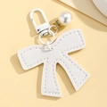 Close-up of white PU leather bow keychain with pearl pendant and rhinestone details - White
