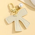 Close-up of cream leather bow pendant with white stitching and pearl detail charm - Off White