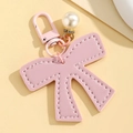 Macro detail of pink leather bow charm with pearl rhinestone and matching metal buckle - Pink