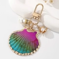 Close-up of gradient shell keychain with round white pearl on artistic display tray - Multicolor